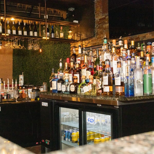 A well-stocked bar at Manzil Fine Indian Dining with various liquor bottles, wine, and glassware.